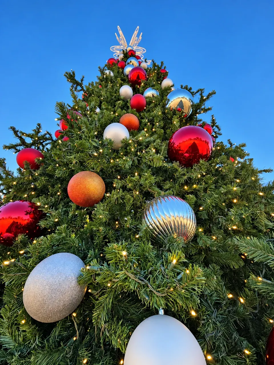 Red, silver and gold ornaments on a community Christmas tree in daylight