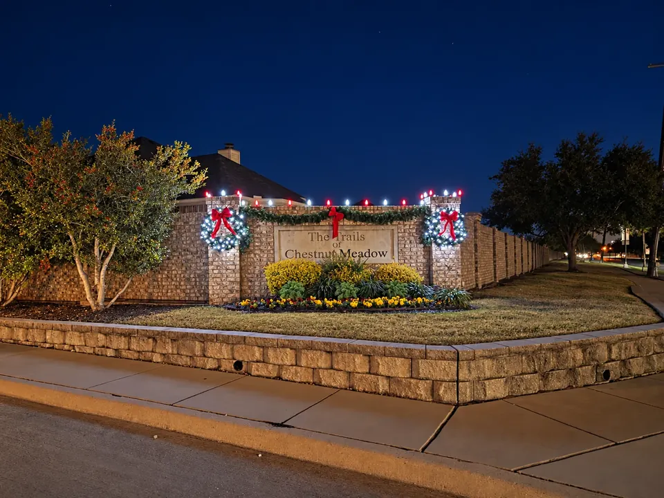 Christmas wreaths and roofline lights decorating a neighborhood entrance