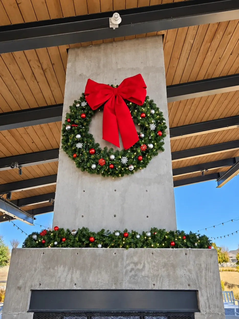 Christmas wreath with a red bow and matching garland at a community pavilion